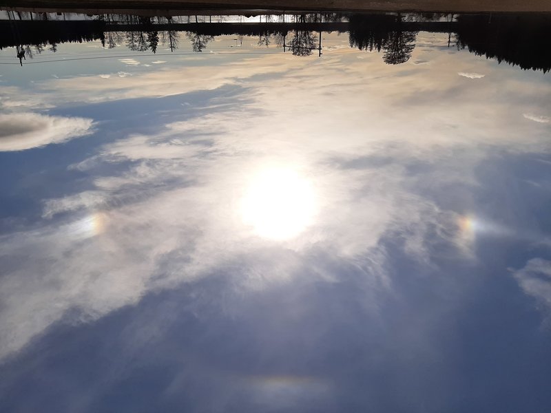 Bisolar till vänster och höger. Upper tangent arc ovanför solen.  Början av Parhelic circle sticker ut från den vänstra bisolen (avsevärt längre visuellt).